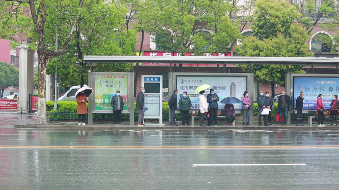 雨中公交站台候车的人 