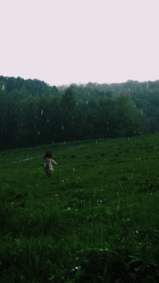 女孩雨中在绿色草地上奔跑