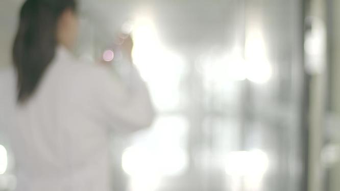 逆光前行医生科研实验人员手拿烧杯向前背影