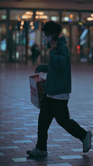 年轻男性手提购物袋走在街上 竖屏