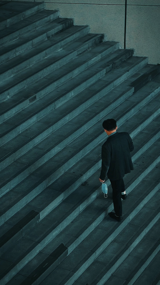 男人手拿口罩上楼梯