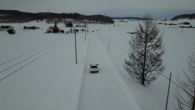 航拍汽车行驶在日本北海道冬季雪原乡村公路