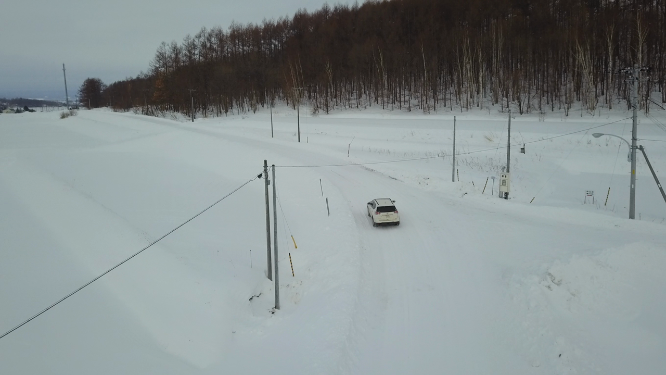 航拍汽车行驶在日本北海道冬季雪原乡村公路