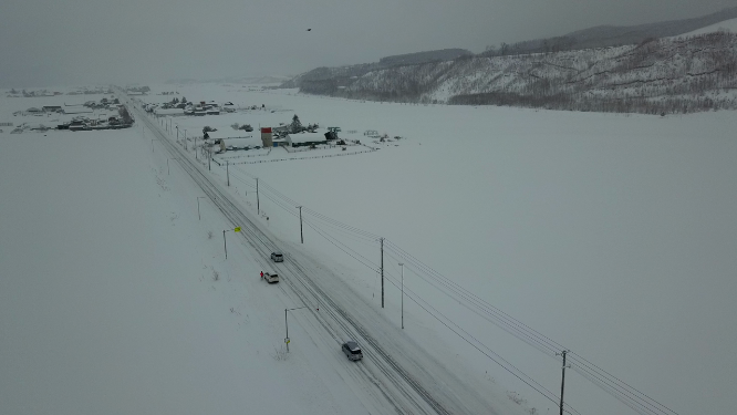 航拍汽车行驶在日本北海道冬季雪原乡村公路