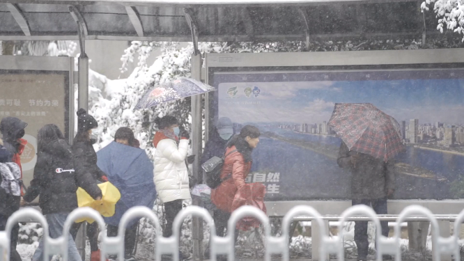 下雪天公交站等车的市民 