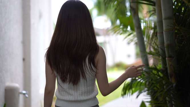 女孩愉快走在林荫小道上 