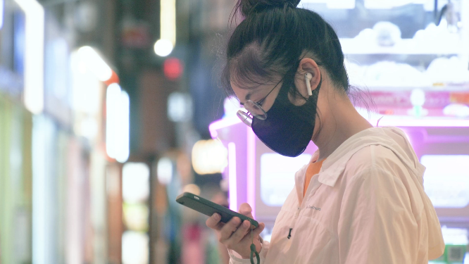 女孩坐在商场等人玩手机