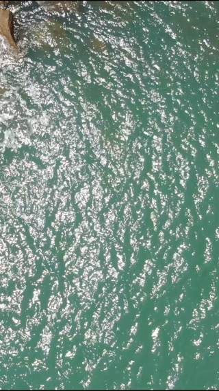 航拍蓝色海边礁石海浪