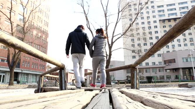 两个年轻情侣散步依偎的背影秀恩爱
