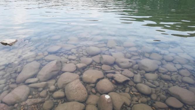 鹅卵石清澈水面随微风缓缓流淌背景