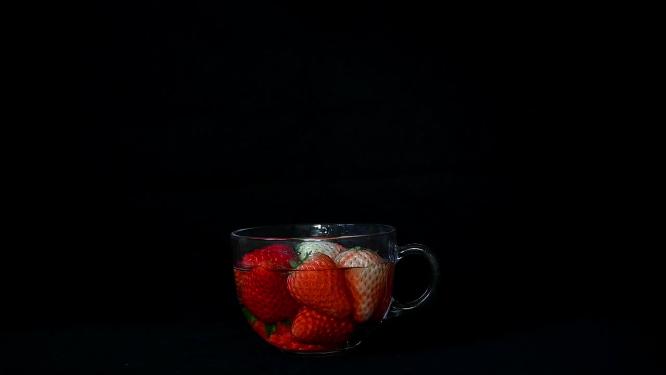 草莓落入玻璃杯中溅起水花的慢镜头