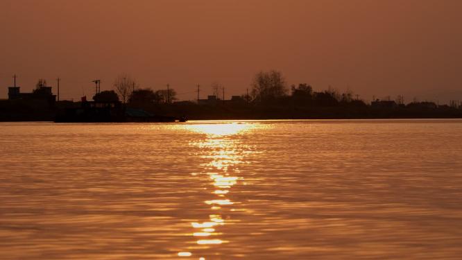 傍晚夕阳落日逆光金色水面轮船剪影