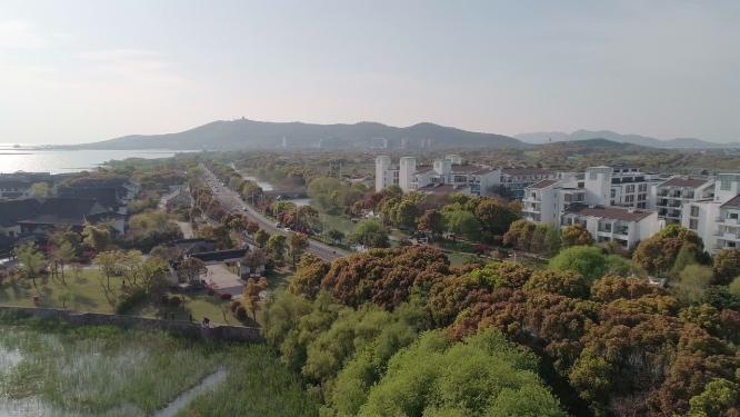 4k航拍，苏州太湖边。沿太湖大道，蓝天白云绿树掩映下的湖边别墅、酒店及公共建筑