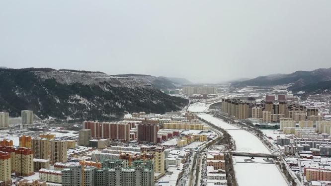 航拍城市雪后的城区与结冰河流