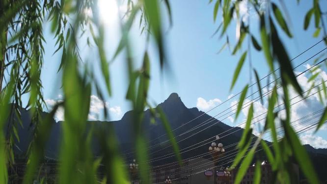 蓝天白云下的山峰柳树做前景