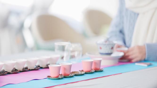 茶艺师拿起一个粉色茶杯